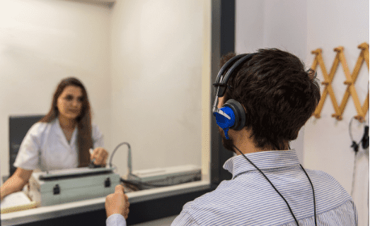 Una médico audióloga realizando una audiometría a un paciente.